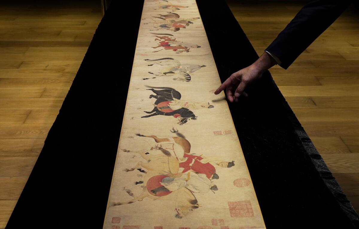 A Sotheby's employee presents the Chinese scroll "Five Drunken Princes Returning on Horseback" during a media preview  