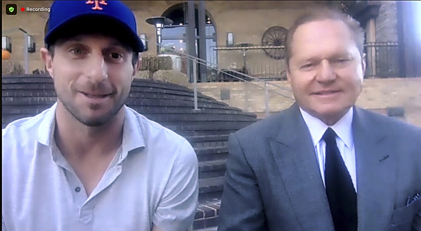This still image from video shows New York Mets pitcher Max Scherzer, left, and agent Scott Boras as they participate in a news conference, Wednesday, Dec. 1, 2021. The Mets and the three-time Cy Young Award winner finalized a $130 million, three-year deal Wednesday, a contract that shattered baseball's record for highest average salary and forms a historically impressive 1-2 atop New York's rotation with Jacob deGrom. (AP Photo)