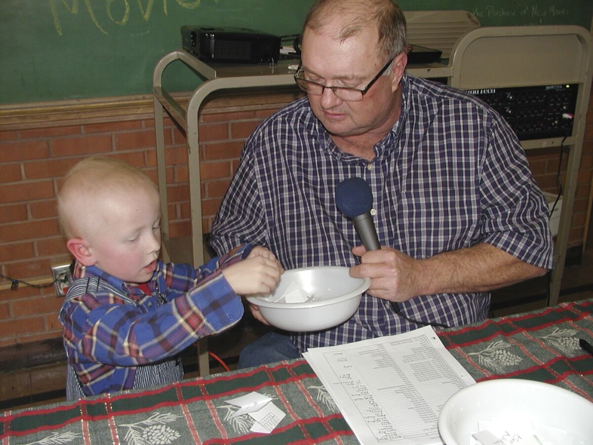 Eric Kuhlman, 3, left, helps master of ceremonies Stan Miller with Norcatur's annual Christmas Drawing