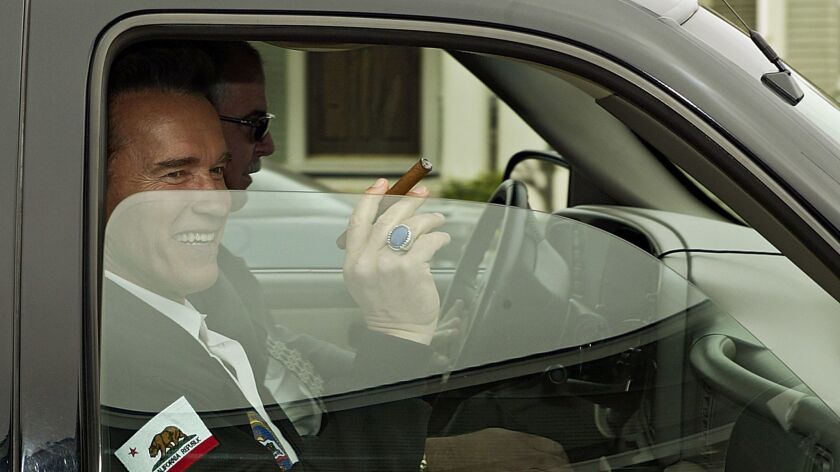 Then-Gov. Arnold Schwarzenegger holds a cigar as he waves to Long Beach residents after visiting the city in 2005.
