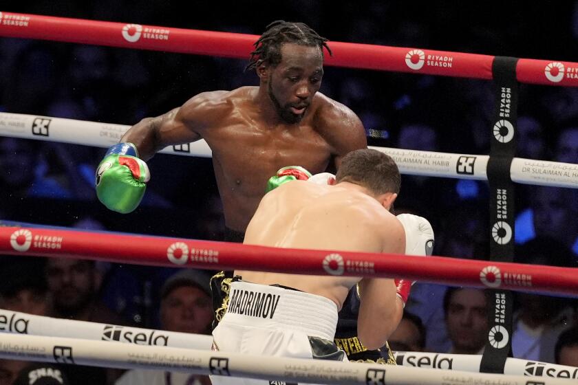 Terence Crawford, top, throws a punch at Israil Madrimov during a super welterweight championship boxing match in Los Angeles, Saturday, Aug. 3, 2024. (AP Photo/Damian Dovarganes)