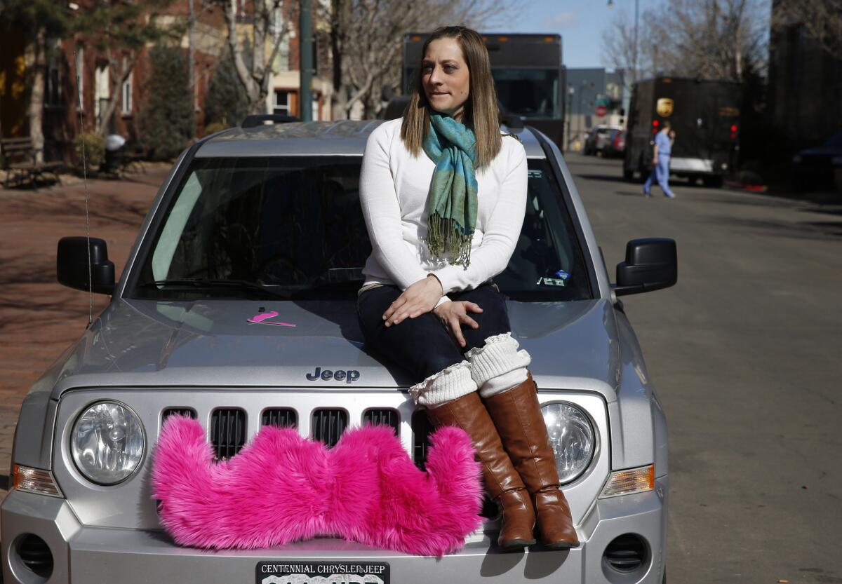 Lyft driver Brittany Cameron sits on the hood of her own vehicle, which she uses to give rides, in downtown Denver.