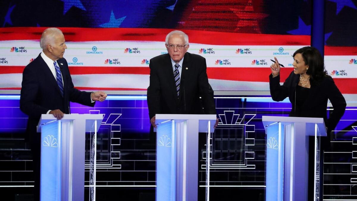 Sen. Kamala Harris and former Vice President Joe Biden, left, speak as Sen. Bernie Sanders (I-VT) looks on during the second night of the first Democratic presidential debate on June 27 in Miami.