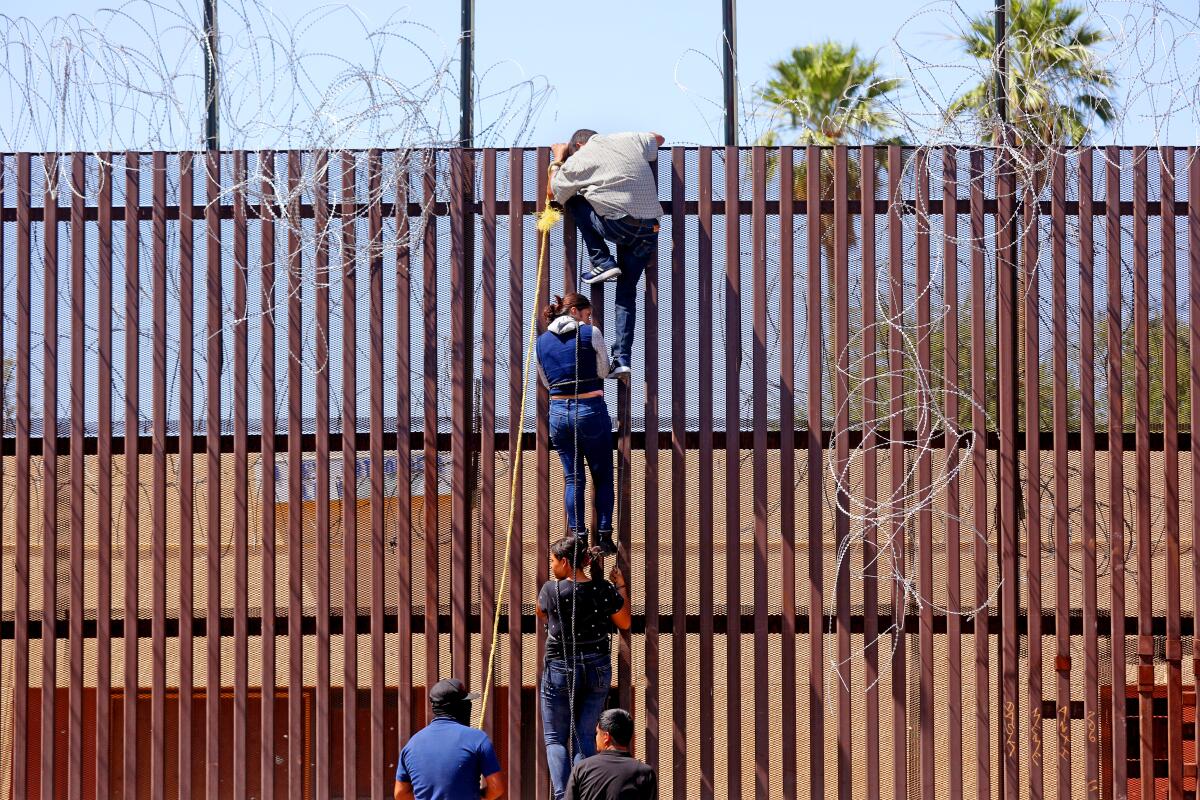 Migrantes intentan saltar el muro fronterizo entre Mexicali, México y Calexico, California, en mayo.