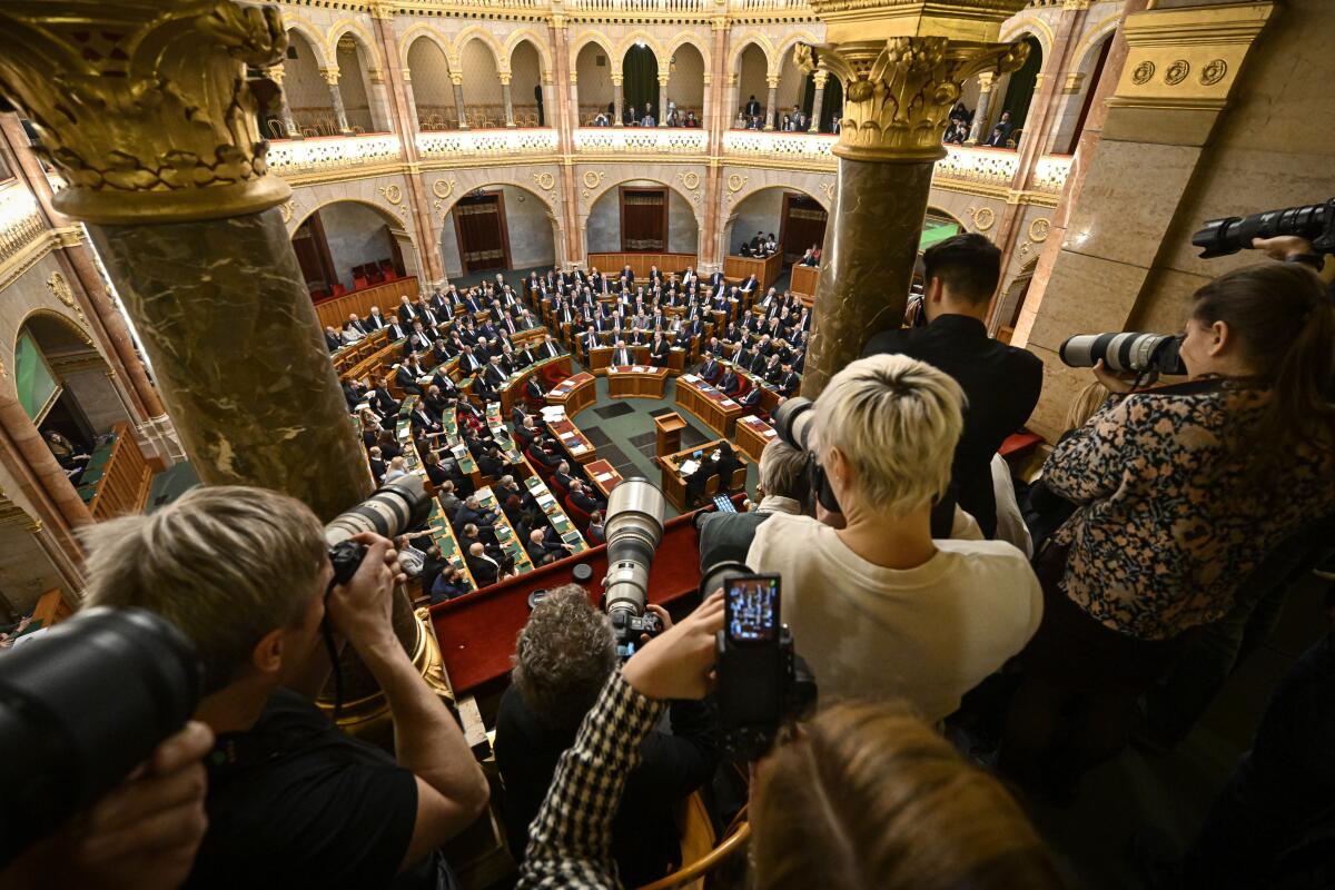 Photographers take pictures as Hungarian Prime Minister Viktor Orban addresses parliament.