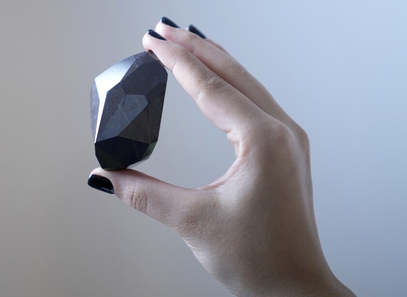Una empleada de Sotheby's de Dubái muestra el diamante negro de 555,55 quilates llamado "El Enigma" 