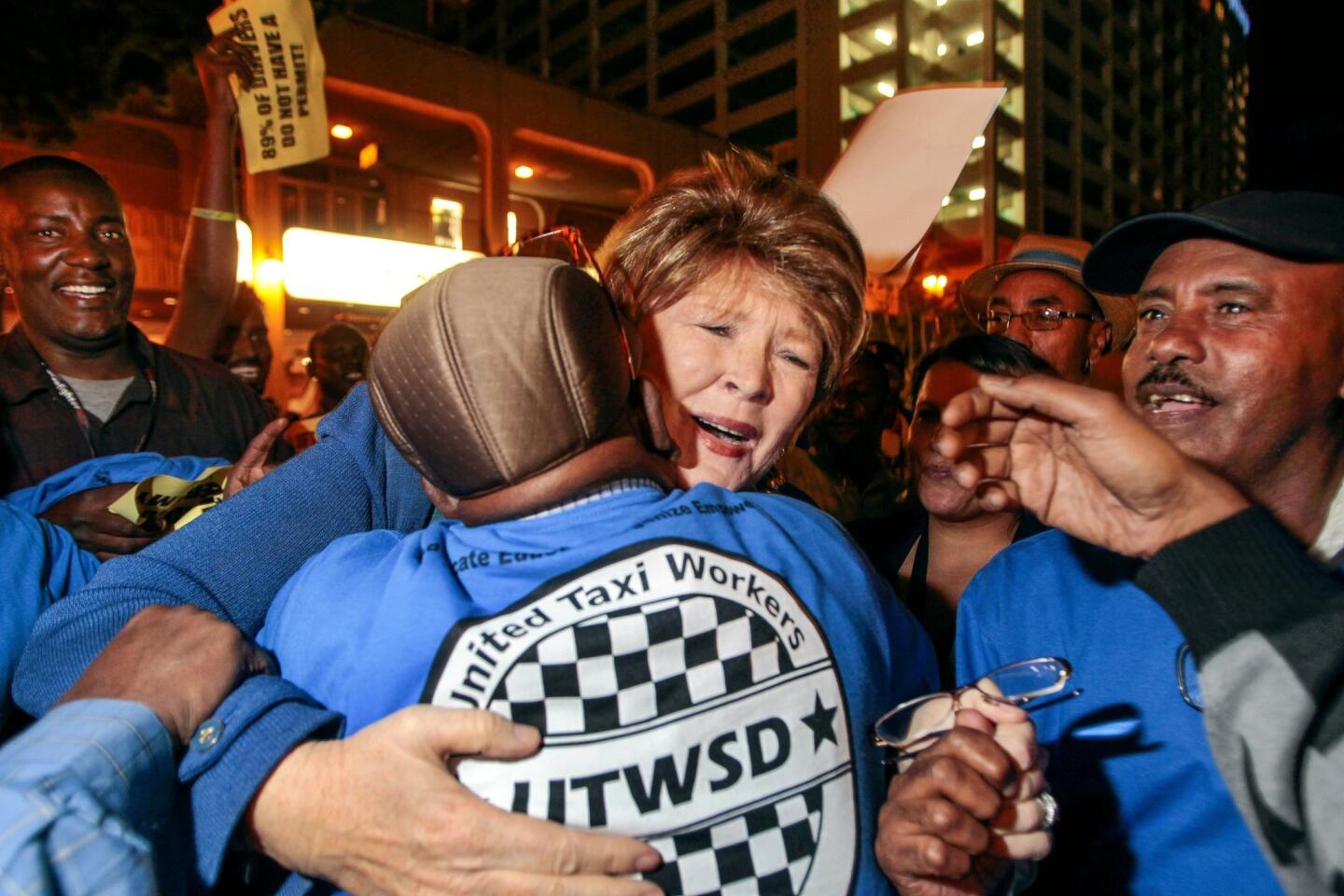 San Diego City Councilwoman Marti Emerald receives a hug while she is swarmed by cab drivers as they celebrate.