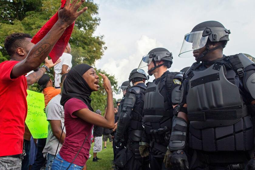 A protester yells at police officers in riot gear after being forced off the motor way in front of the the Baton Rouge Police Department Headquarters in Baton Rouge, La., Saturday, July 9, 2016. Several hundred protesters, including members of the New Black Panther party, blocked the road causing police to close the road and move the crowd with riot police. (AP Photo/Max Becherer)