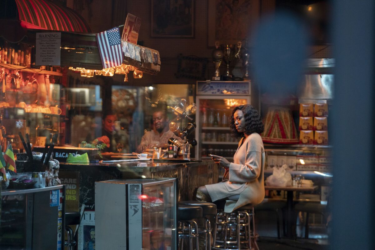 A woman, seen through the window, sits at a restaurant bar