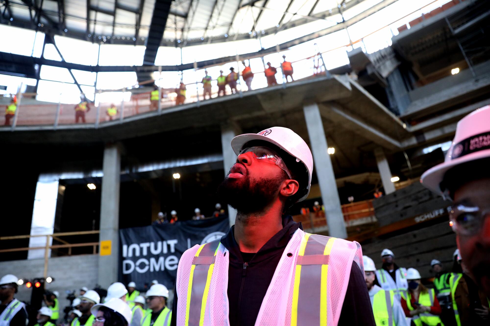 Clippers forward Paul George looks overhead to watch construction workers put a steel beam in place.