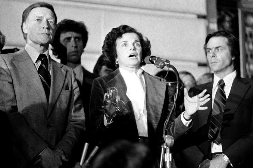 Acting Mayor Dianne Feinstein with Police Chief Charles Gain at left, addresses the more than 25,000 people jammed around San Francisco's City Hall, Nov. 28, 1978 as city residents staged a spontaneous memorial service for slain officials Mayor George Moscone and Supervisor Harvey Milk. Man at right is not identified. (AP Photo)