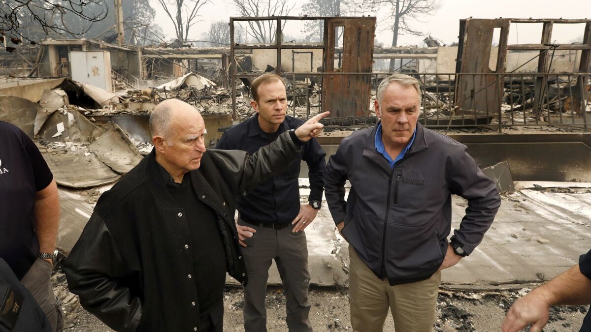 Gov. Jerry Brown. left, and Secretary of the Interior Ryan Zinke, right, tour downtown ParadiseCalif., on Nov. 14, 2018.