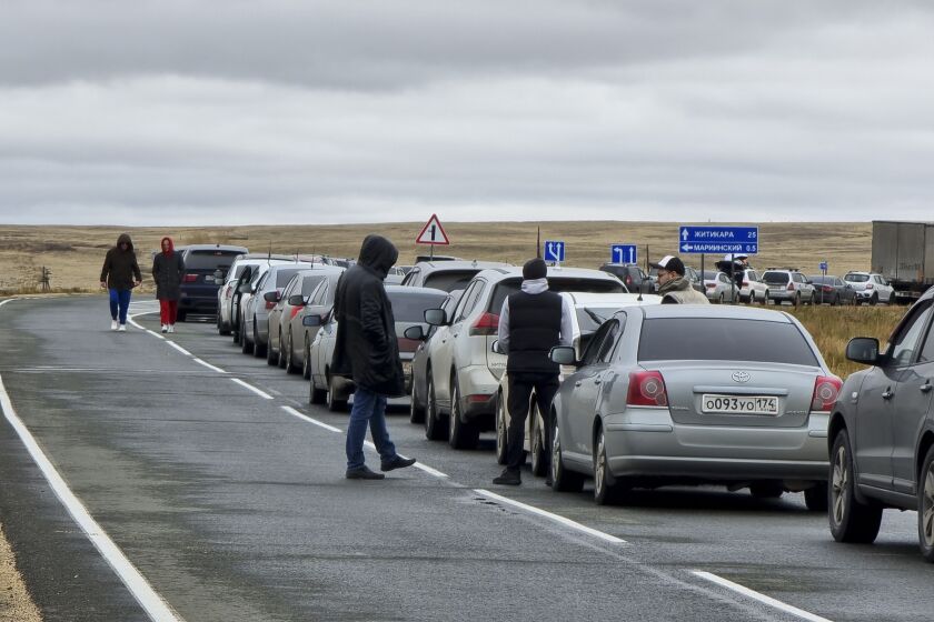 La gente camina junto a sus automóviles haciendo fila para cruzar la frontera de Rusia con Kazajistán en el paso fronterizo de Mariinsky, a unos 400 kilómetros (250 millas) al sur de Chelyabinsk, Rusia, el martes 27 de septiembre de 2022. (AP Foto)