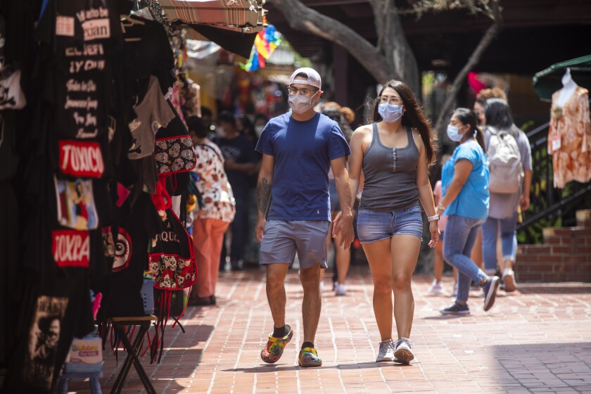 A couple wearing face masks stroll along Olvera Street