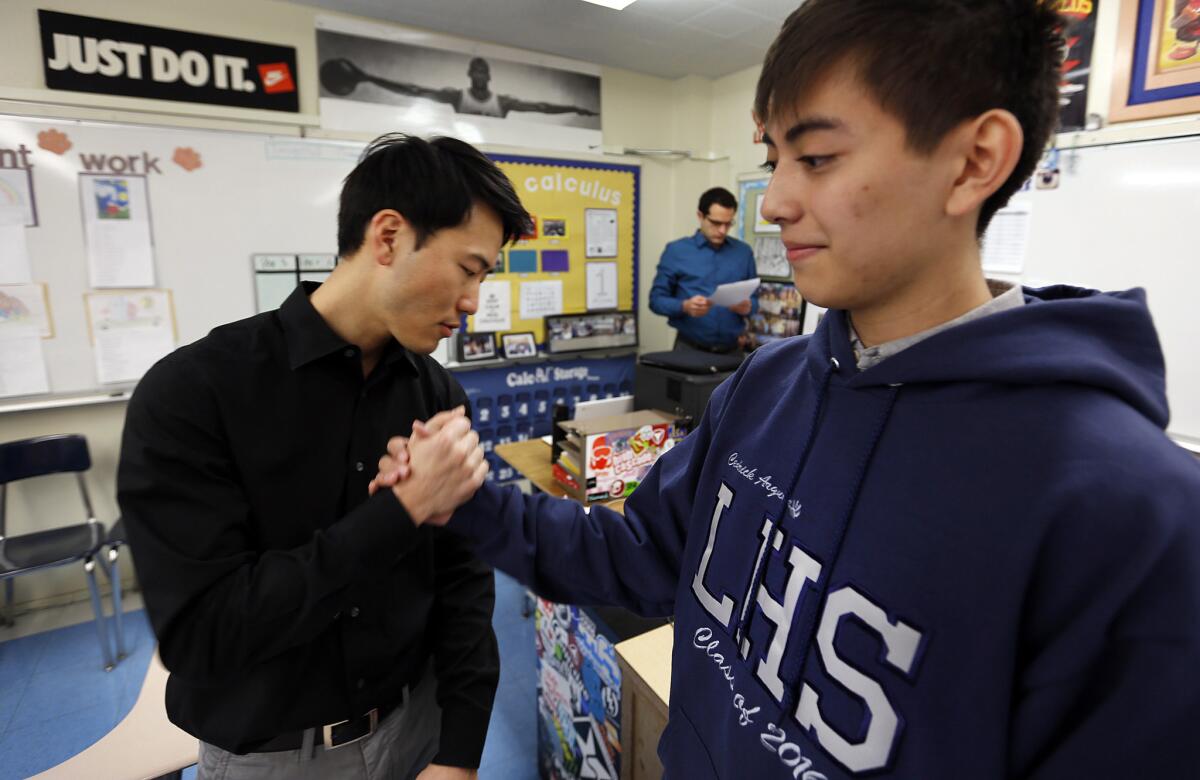 Cedrick Argueta, right, is congratulated by his mathematics instructor Anthony Yom, left, in his Calculus classroom.