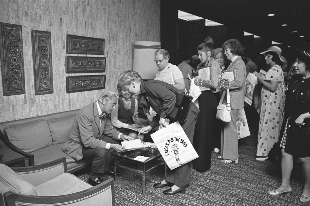 Man signs books next to a line of people