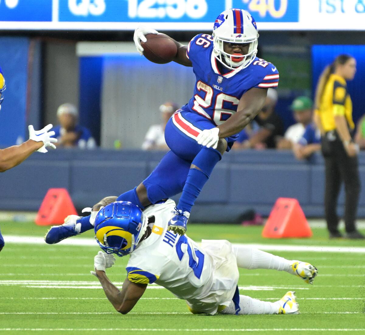 Bills running back Devin Singletary picks up yards as Rams cornerback Troy Hill brings him down.