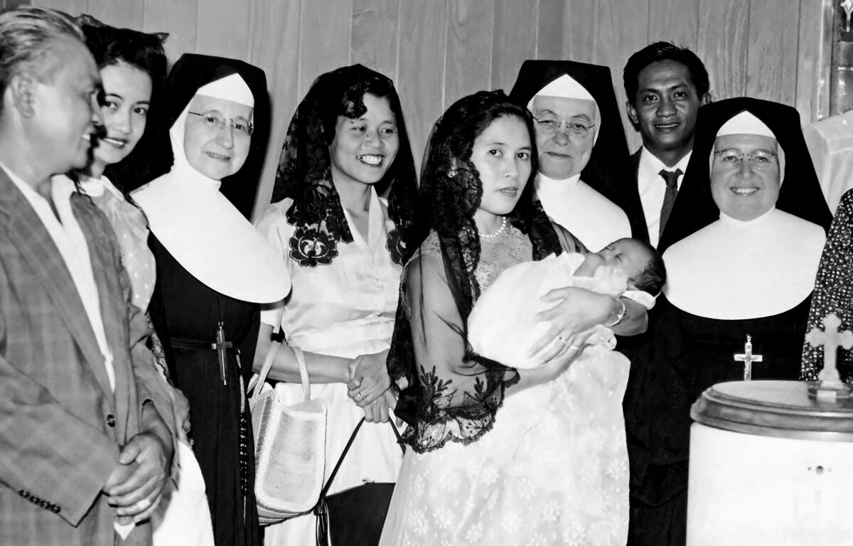 Joe Lumarda in his mother's arms at his christening, with family members and nuns by their side
