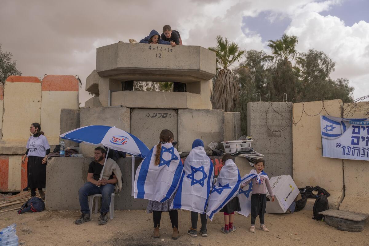 Varias personas esperan junto al paso fronterizo israel de Nitzana, en la frontera con Egipto, el 27 de febrero de 2024 en protesta por la entrada de ayuda humanitaria a Gaza sin que se haya liberado a todos los rehenes capturados por Hams. (AP Foto/Ohad Zwigenberg)
