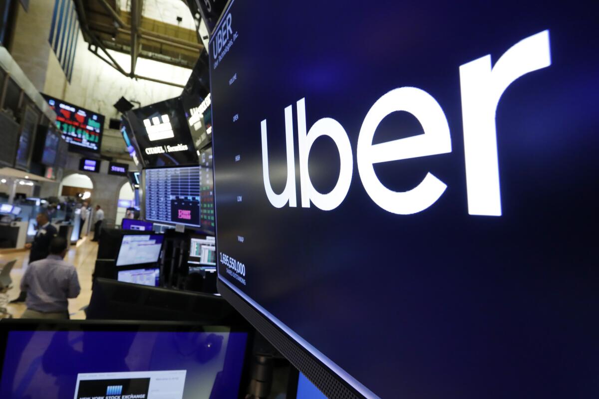 FILE - The logo for Uber appears above a trading post on the floor of the New York Stock Exchange, Friday, Aug. 9, 2019. Uber’s ride-hailing service continued to gain momentum in the second quarter as consumers headed back to offices and started traveling more amid an easing in pandemic restrictions. Passengers took a total of 1.87 billion trips on Uber during the spring and early summer, a 24% increase from the same time last year. (AP Photo/Richard Drew, File)