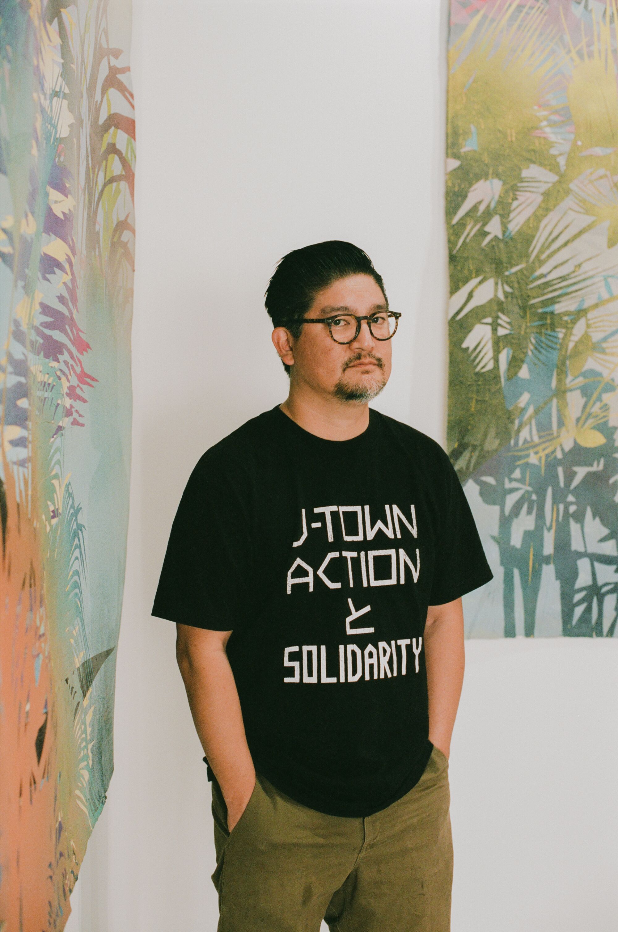 Devon Tsuno stands in front of his paintings on display at Residency Art Gallery in Inglewood, CA.
