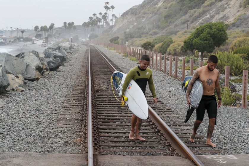 San Clemente, CA, Thursday, August 5, 2022 - Surfers cross the railroad tracks near San Clemente's North Beach at Dije Court. San Clemente City Council is proposing an abortion ban. (Robert Gauthier/Los Angeles Times)