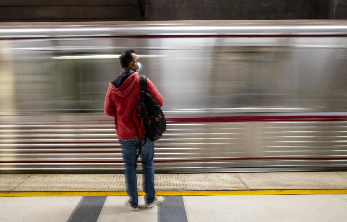 A commuter waits at Pershing Square station as a Metro Red Line train arrives