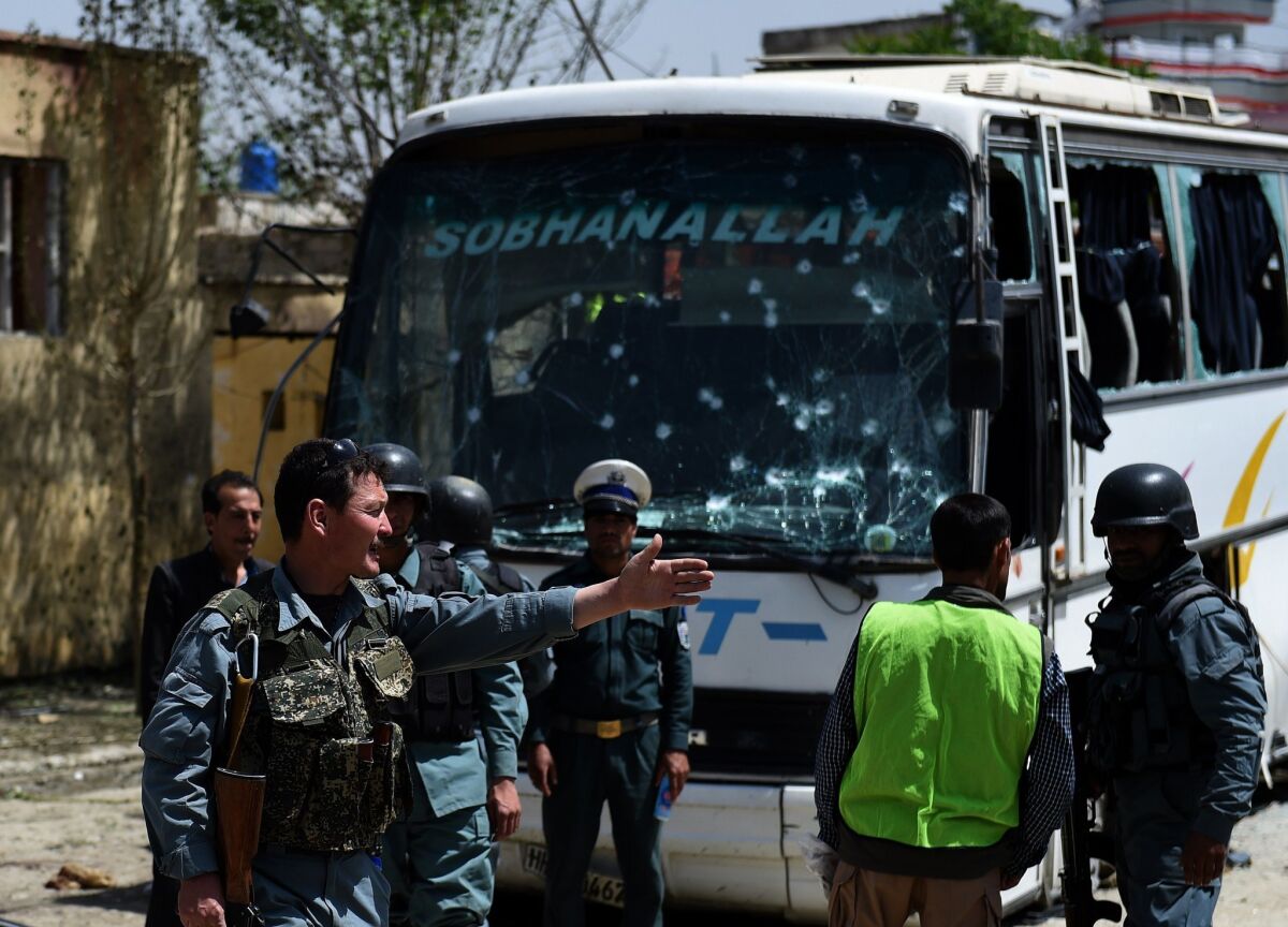 Afghan security personnel inspect the scene of a suicide attack on a bus in Kabul that was transporting government employees. Taliban attacks on Monday also killed 17 policemen in remote Badakhshan province.