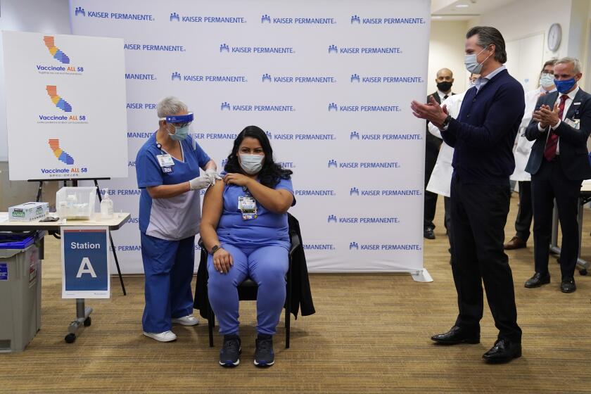 California Gov. Gavin Newsom looks on, far right, as ICU nurse Helen Cordova receives the Pfizer-BioNTech COVID-19 vaccine at Kaiser Permanente Los Angeles Medical Center in Los Angeles, Monday, Dec. 14, 2020. (AP Photo/Jae C. Hong)