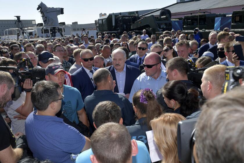 Belarusian President Alexander Lukashenko, center, surrounded by his bodyguards listens to an employee of the Minsk Wheel Tractor Plant in Minsk, Belarus, Monday, Aug. 17, 2020. Workers heckled President Alexander Lukashenko as he visited a factory and strikes grew across Belarus, raising the pressure on the authoritarian leader to step down after 26 years in office. (Andrei Stasevich/BelTA Pool Photo via AP)