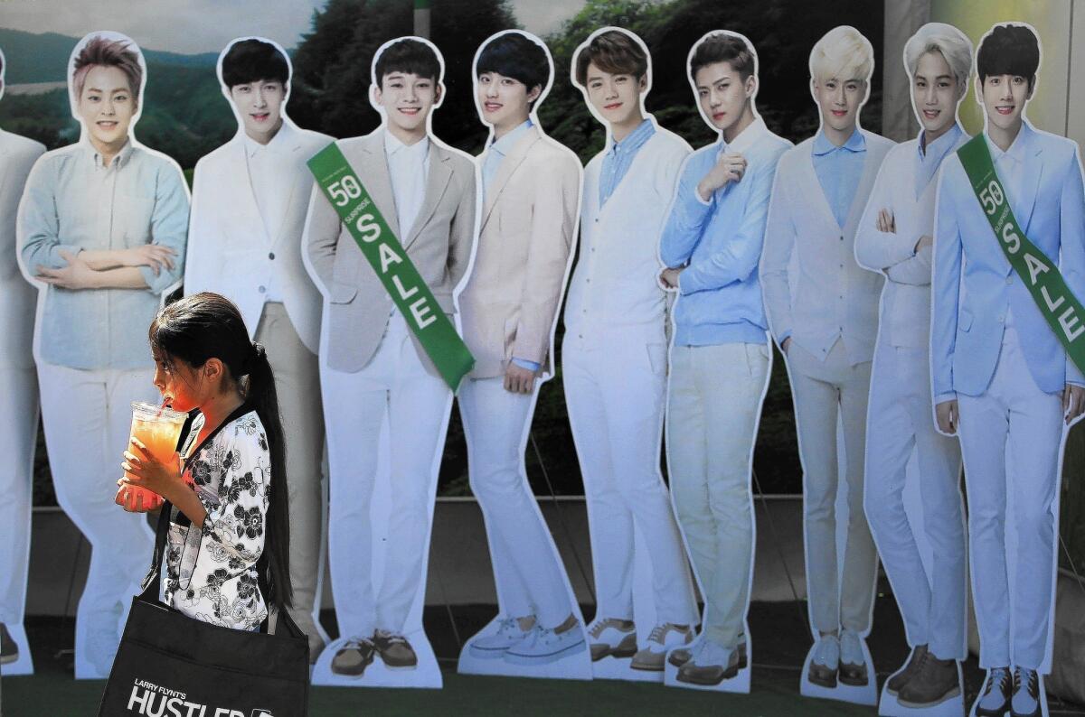 A young festival-goer walks past cardboard cutouts of Korean boy band EXO at the Los Angeles Korean Festival at Seoul International Park in Koreatown.