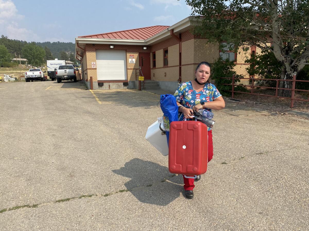 A nurse carries coolers