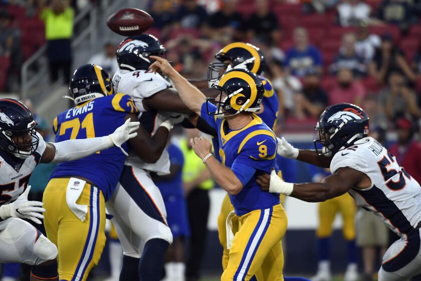 LOS ANGELES, CA - AUGUST 24: Quarterback John Wolford #9 of the Los Angeles Rams throws a pass under pressure from linebacker Justin Hollins #52 and defensive end DeMarcus Walker #57 of the Denver Broncos during the first half at Los Angeles Memorial Coliseum on August 24, 2019 in Los Angeles, California. (Photo by Kevork Djansezian/Getty Images)