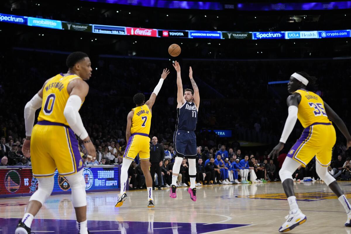Mavericks guard Luka Doncic shoots a three-pointer over Troy Brown Jr of the Lakers.