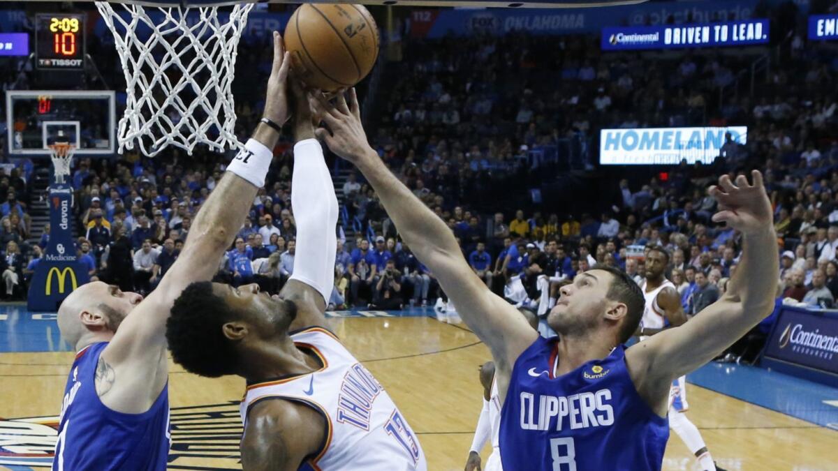 Oklahoma City's Paul George reaches for a rebound between the Clippers' Marcin Gortat, left, and Danilo Gallinari.