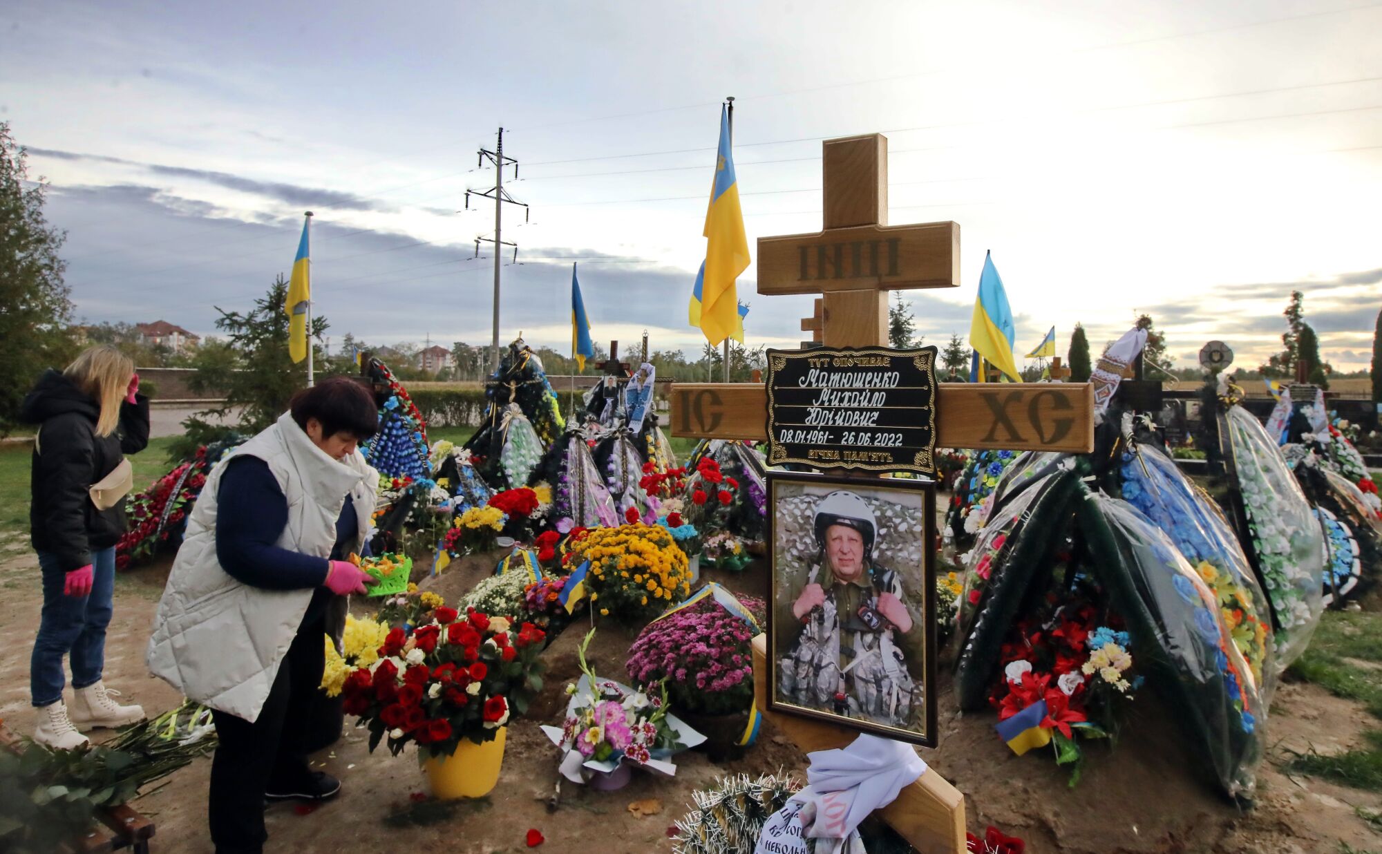 İki kadın çiçekler, haçlar ve diğer eşyalarla süslenmiş mezarları ziyaret ediyor