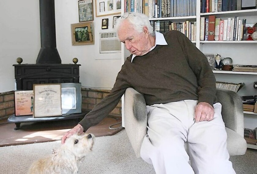 Joseph Bell pets his dog, Gia, in his home office, where he did much of his work as a freelance writer and columnist for the Daily Pilot.