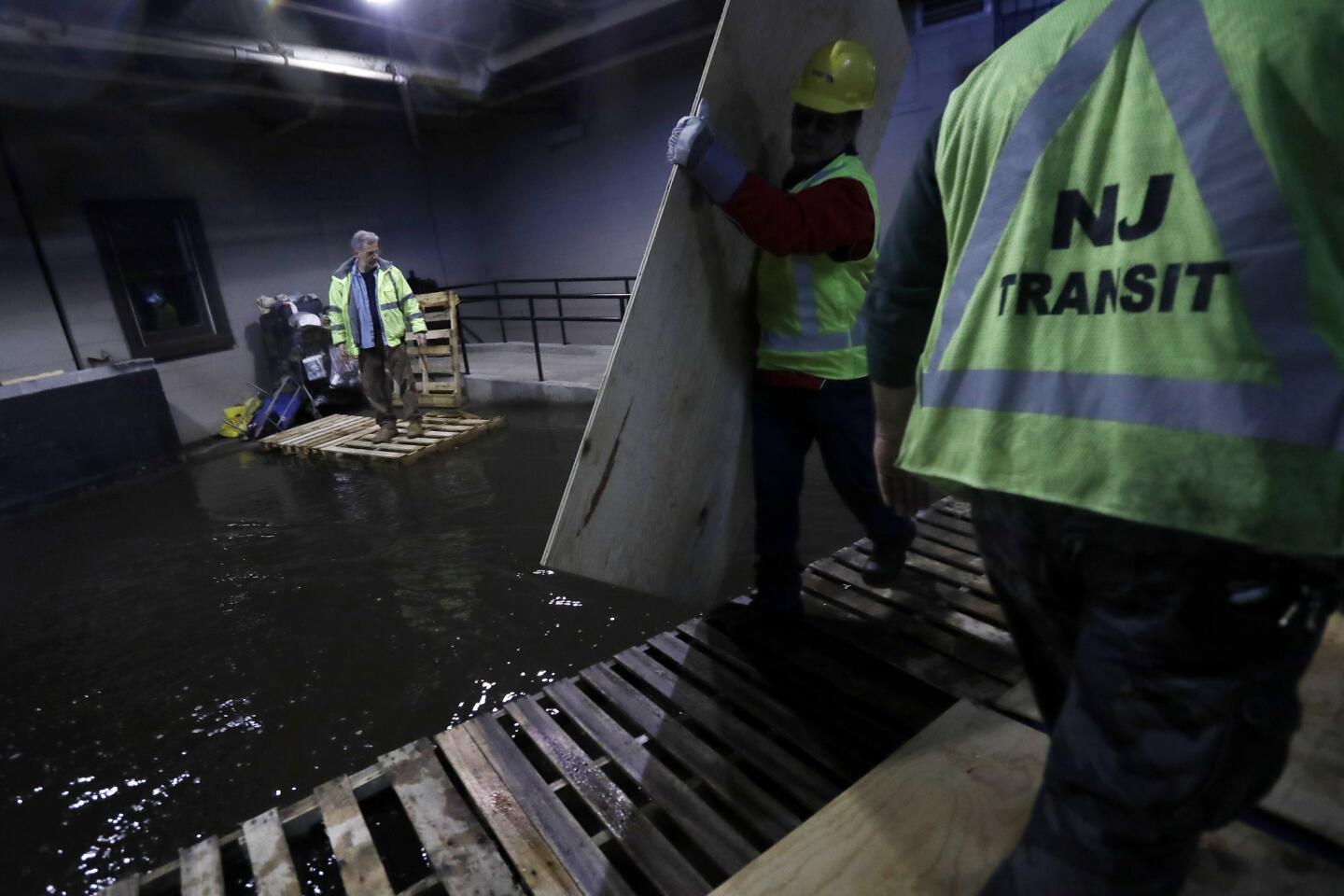 New Jersey Transit workers lay down pallets and boards for commuters to walk on a flooded hallway adjacent to the site of a train crash at the Hoboken Terminal on Sept. 30, 2016.