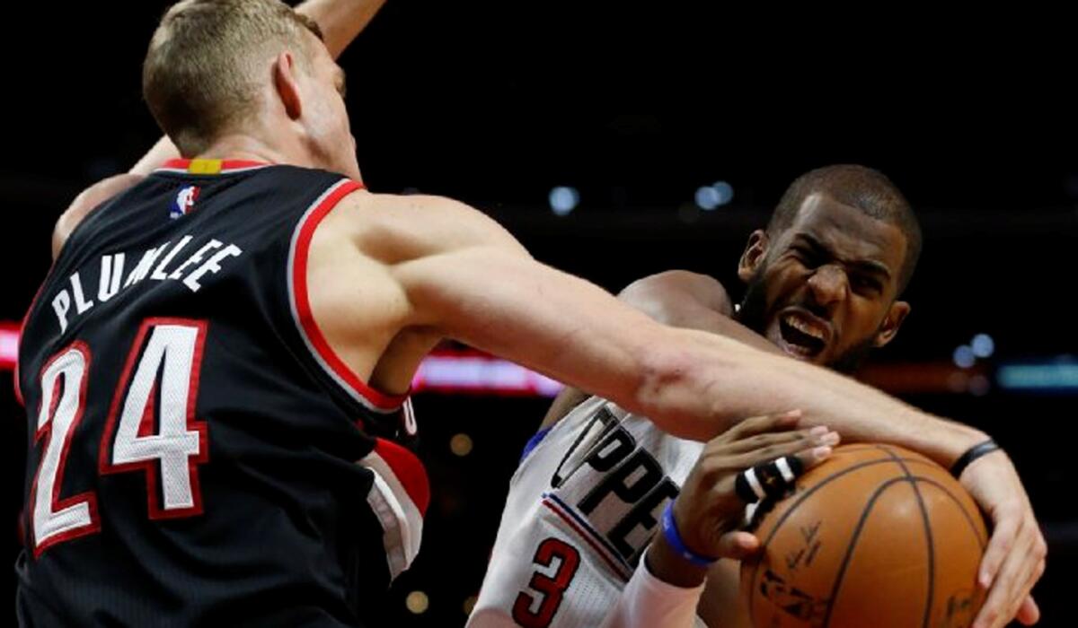 Clippers guard Chris Paul wrestles for the ball with Trail Blazers center Mason Plumlee during first half action.