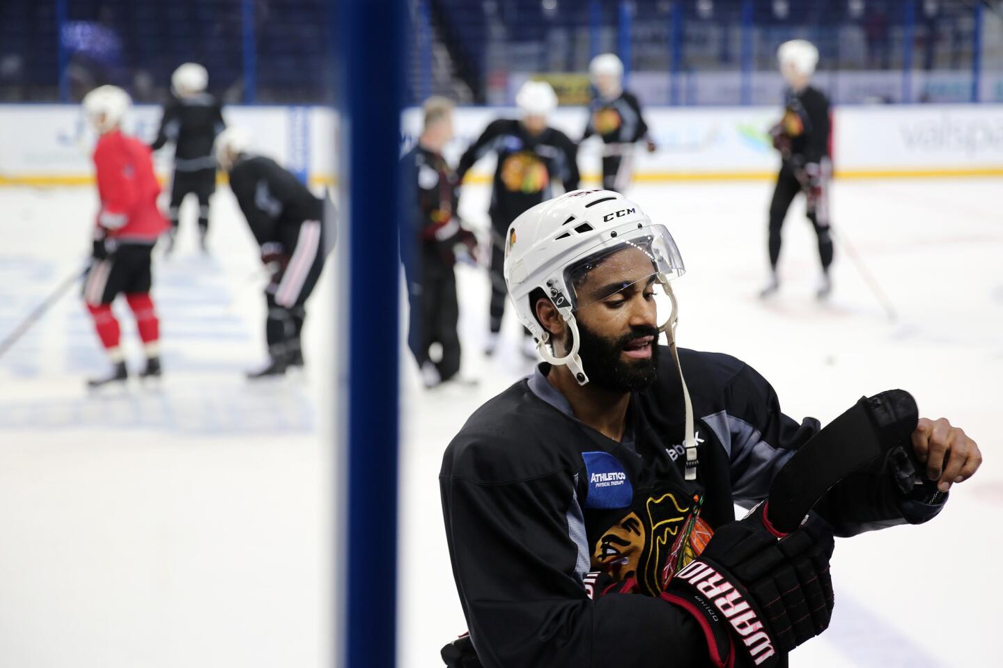 Johnny Oduya pulls tape off his stick during practice.