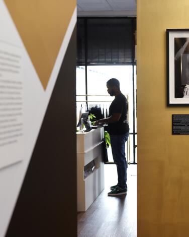 Black-and-white photographs in black frames hang on a gold wall in a museum