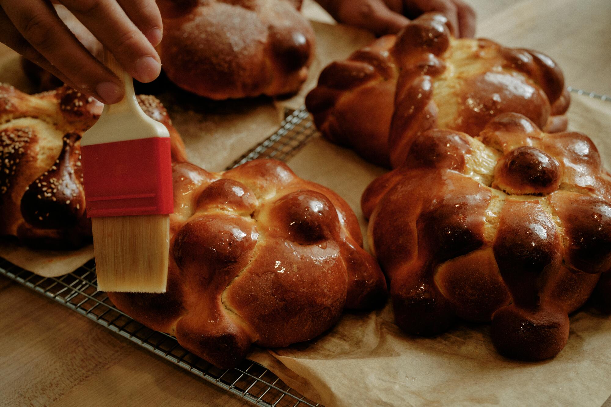 Gusto Bread owner Arturo Enciso brushes melted butter onto freshly baked pan de muerto.