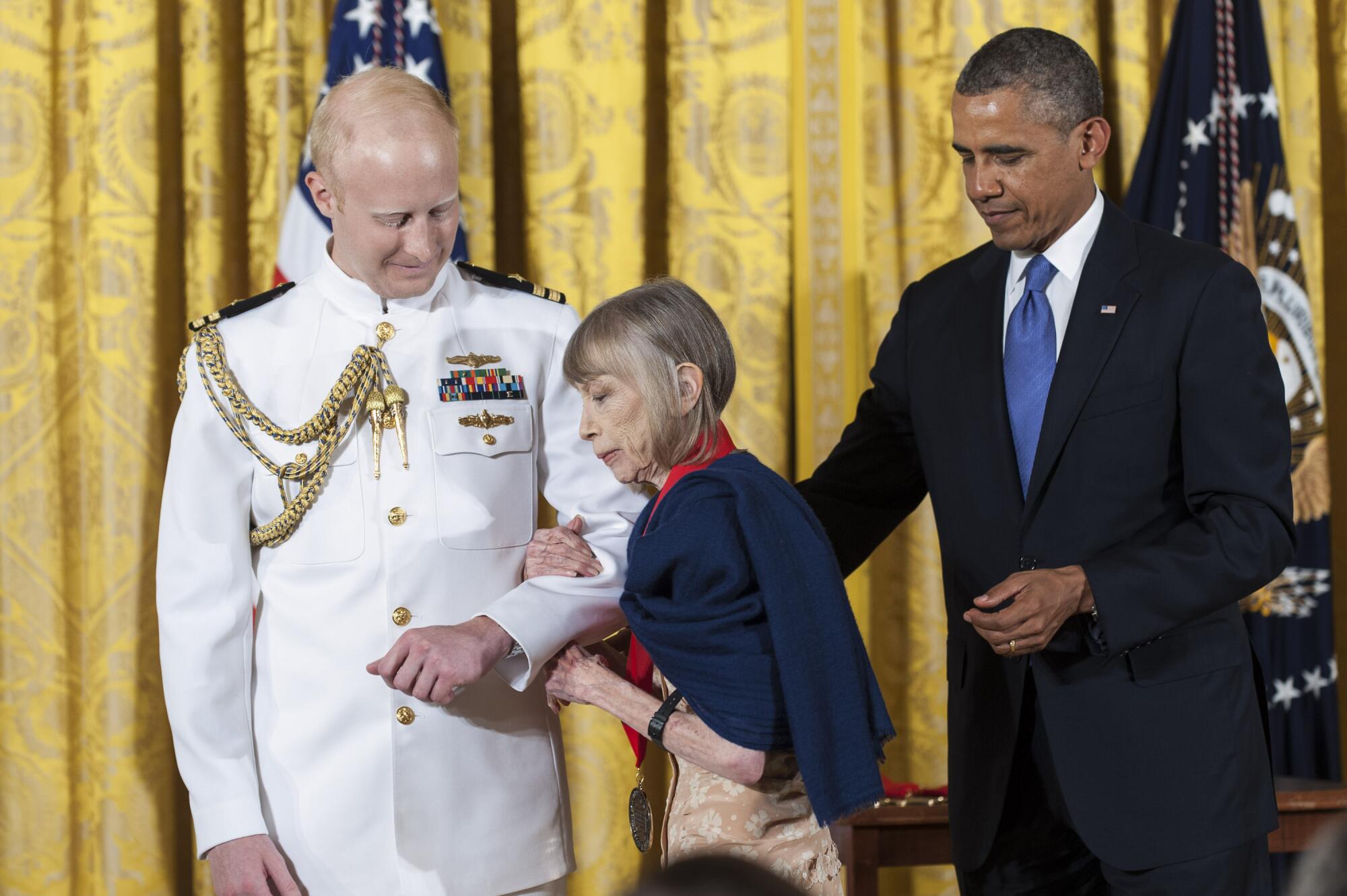 A uniformed official escorts Joan Didion as President Obama looks on.