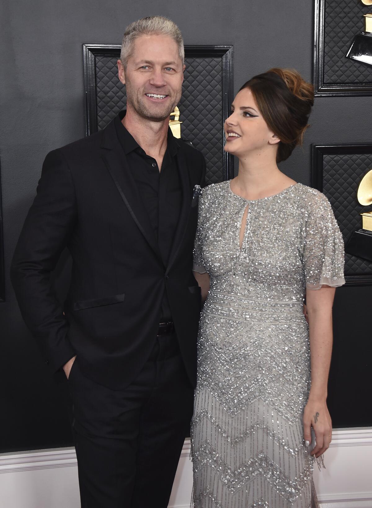 A man and woman pose on a red carpet