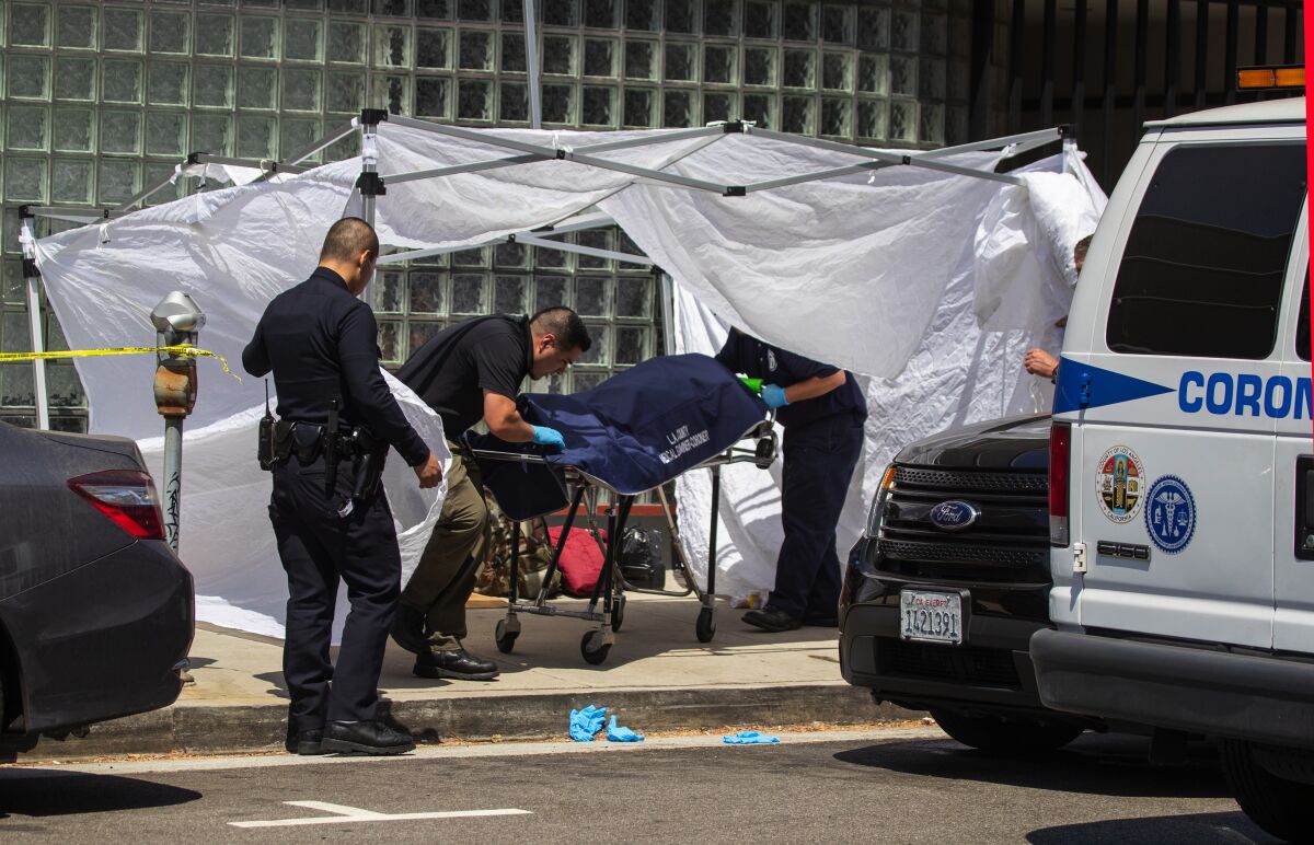 Coroner’s officials remove the body of a homeless man found on the sidewalk at Massachusetts Avenue and Sepulveda Boulevard in Los Angeles on Sept. 1.