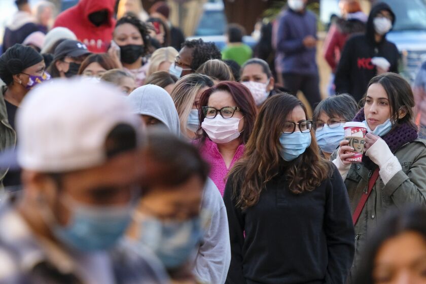 FILE - Black Friday shoppers wearing face masks wait in line to enter a store at the Citadel Outlets in Commerce, Calif., Friday, Nov. 26, 2021. California is bringing back a statewide indoor mask mandate. Gov. Gavin Newsom's administration announced the new mandate will start Wednesday, Dec. 15, 2021, and last until Jan. 15, 2022. (AP Photo/Ringo H.W. Chiu, File)