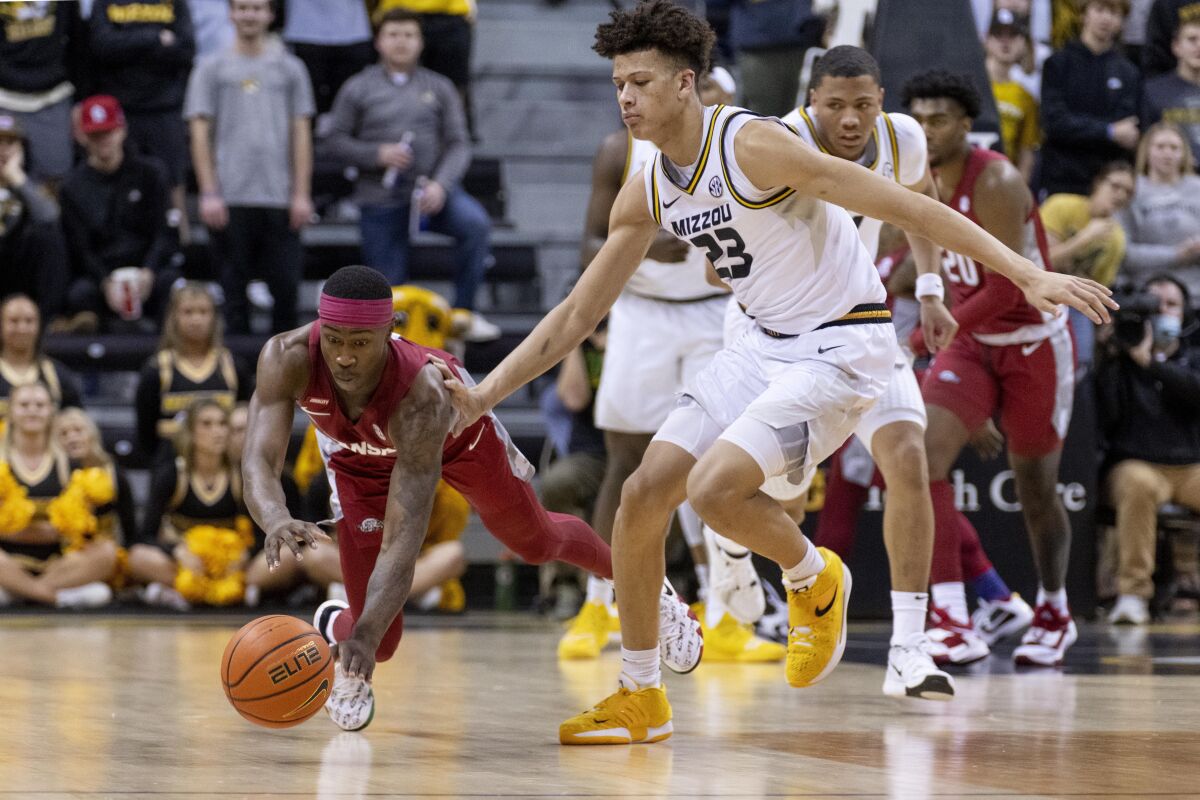 Arkansas' Davonte Davis, left, dives for the ball in front of Missouri's Trevon Brazile, right, during the first half of an NCAA college basketball game Tuesday, Feb. 15, 2022, in Columbia, Mo. (AP Photo/L.G. Patterson)