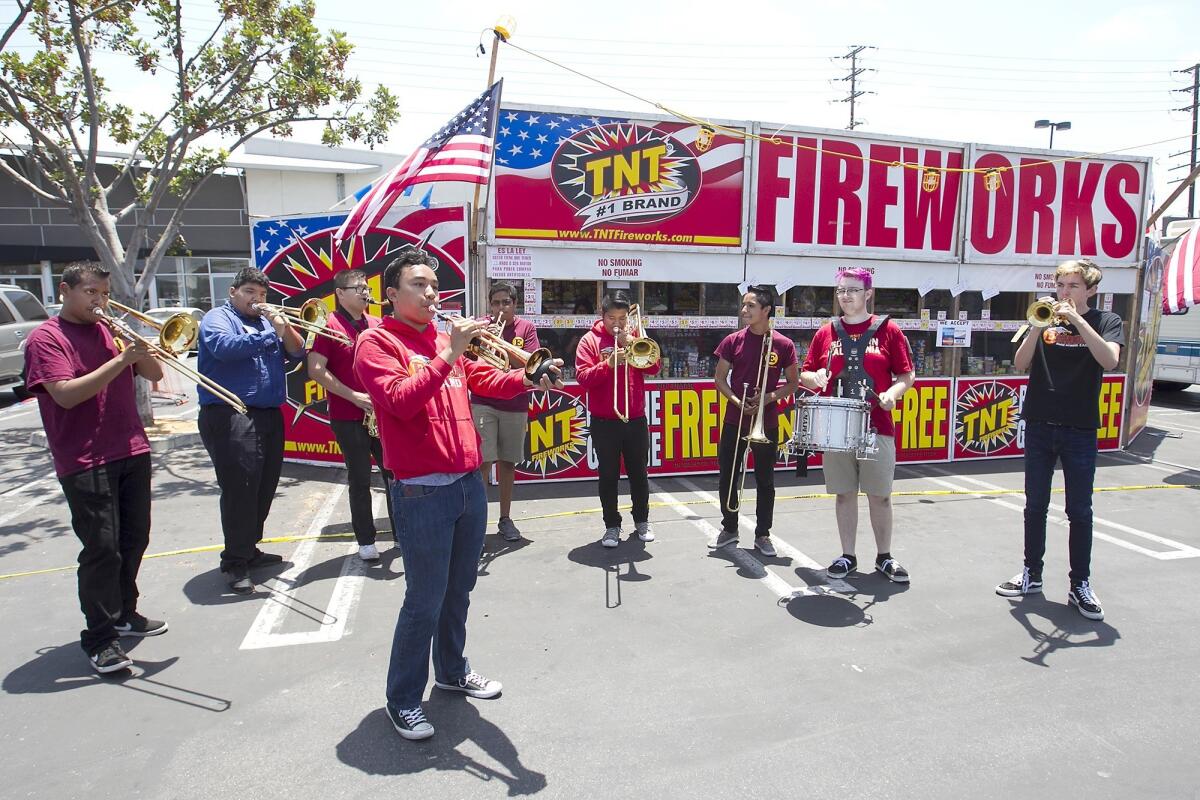 A high school marching band performs in front of a fireworks booth in Costa Mesa.