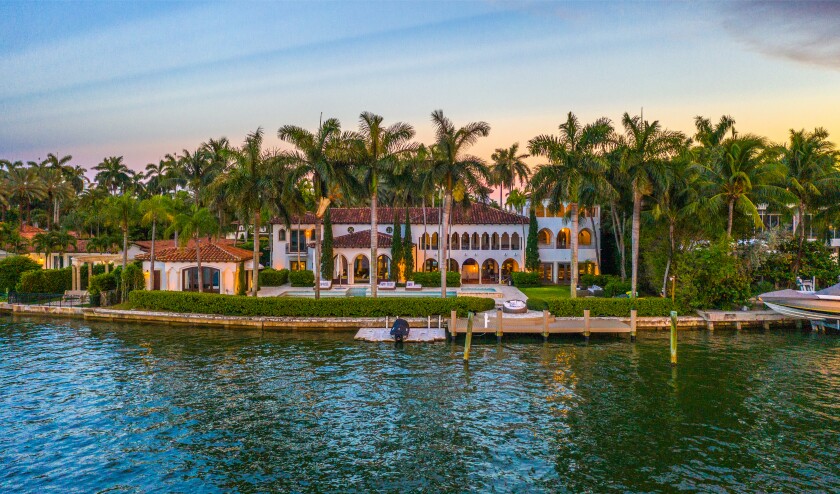 The 11,500-square-foot mansion opens to a palm-topped backyard with a lap pool, private dock and 158 feet of water frontage.