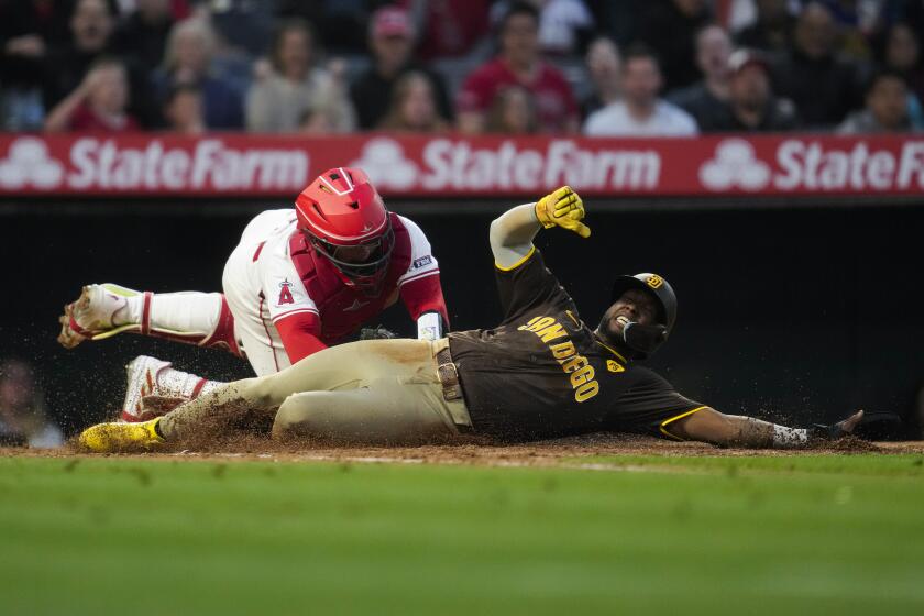 San Diego Padres designated hitter Jurickson Profar, right, is tagged out at home by Los Angeles Angels catcher Logan O'Hoppe during the fifth inning of a baseball game in Anaheim, Calif., Monday, June 3, 2024. (AP Photo/Ashley Landis)